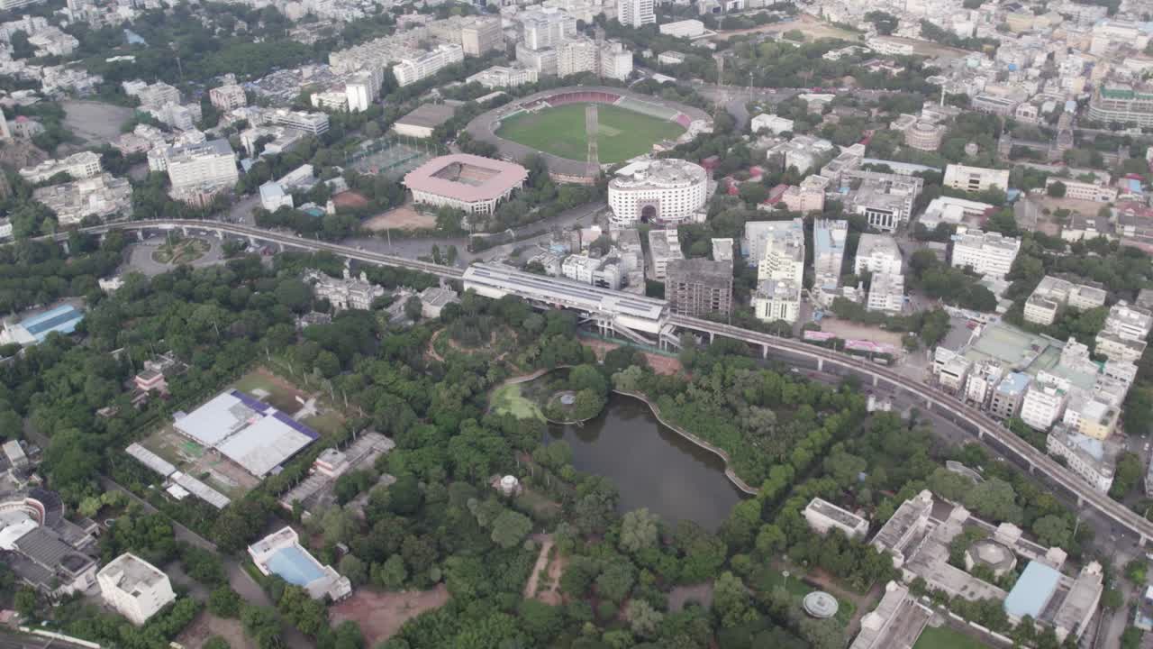 Riprese aeree di uno stadio nelle vicinanze, binari ferroviari paralleli e una stazione della metropolitana nel centro della città.