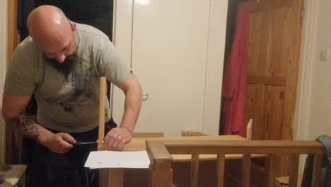 hombre adulto caucásico barbudo ensamblando muebles de pino de paquete plano atornillando juntas tablas