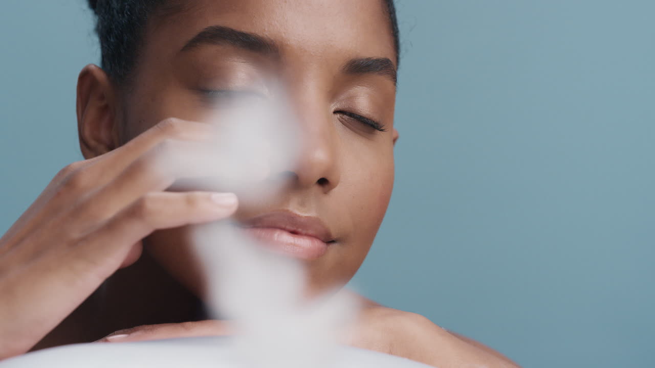 retrato de cerca hermosa joven mujer afroamericana sonriendo tocando las plumas de la cara que caen sobre la piel suave natural acariciando suavemente la tez saludable en cámara lenta concepto de cuidado de la piel