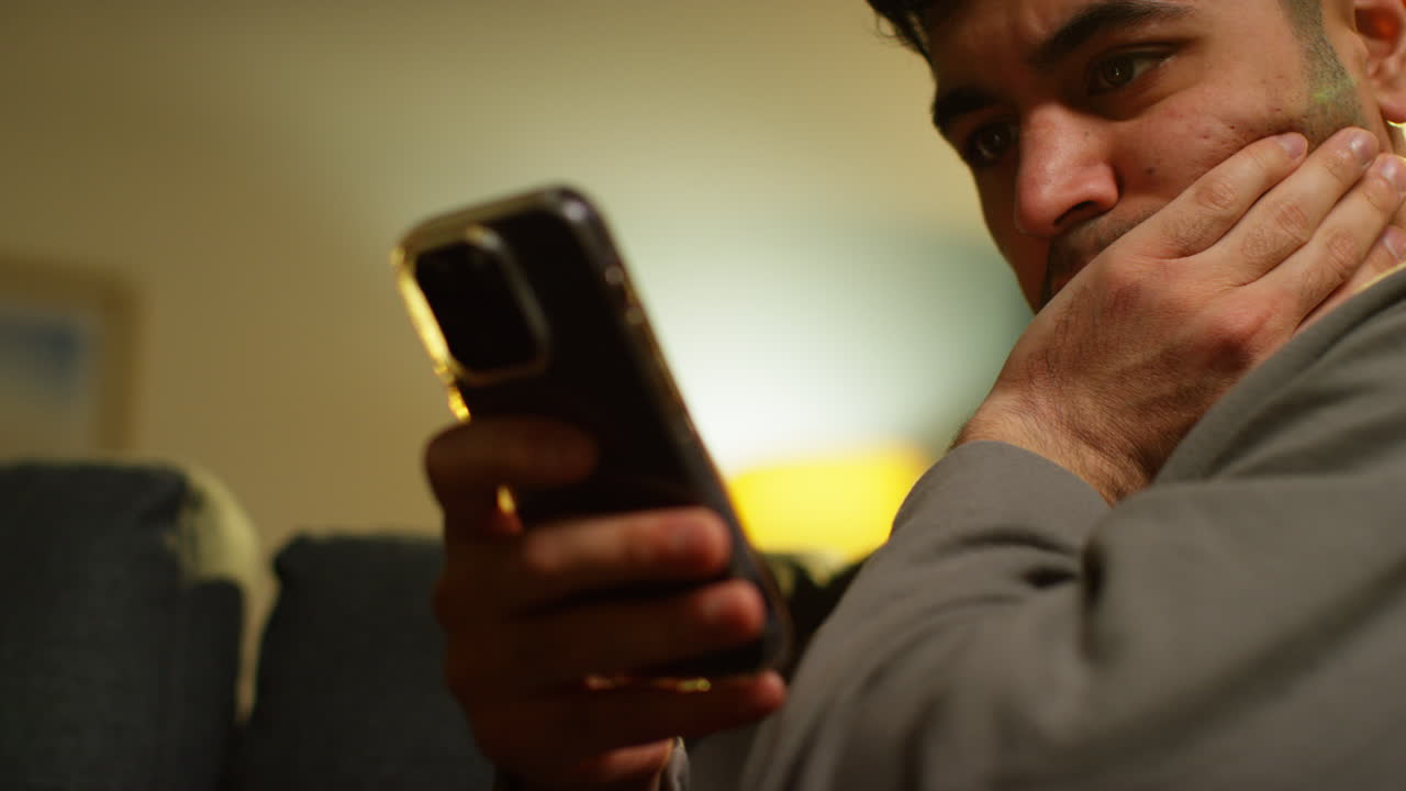 집에서 소파에 앉아 인터넷이나 소셜 미디어 스트리밍 콘텐츠를 스크롤하는 젊은 남자의 클로즈업