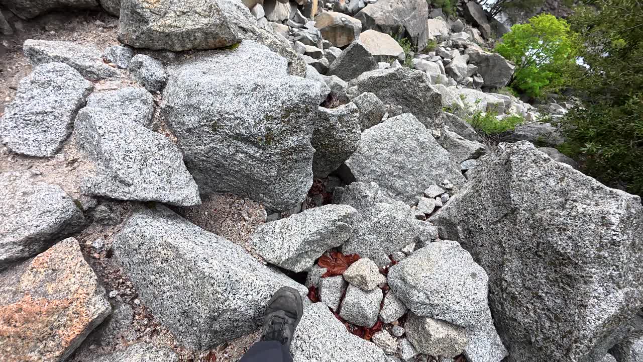Vista in prima persona di un'escursione su un sentiero roccioso verso una maestosa cascata