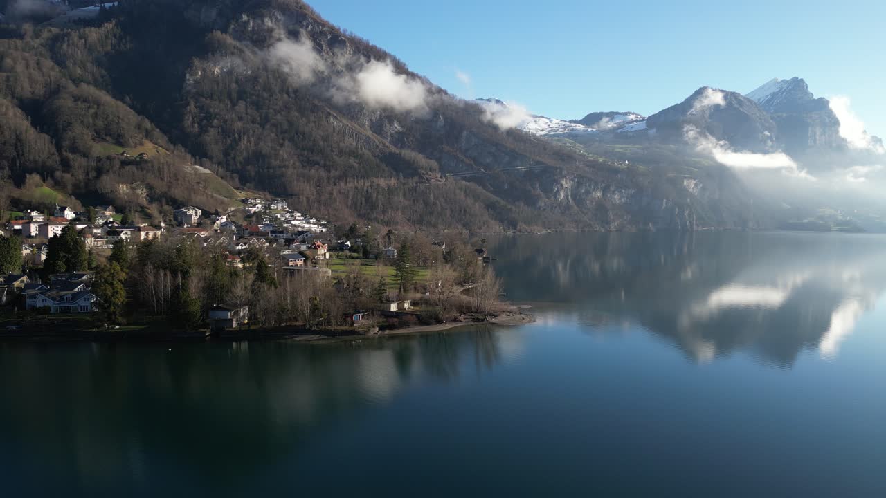 Ripresa drone panoramica di una pittoresca città svizzera sulle rive di un lago calmo, in una luminosa giornata di primavera con cieli azzurri.