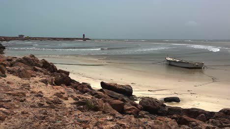 morred fishing boat on beach of djerba in tunisia with sea waves breaking on shore, north africa