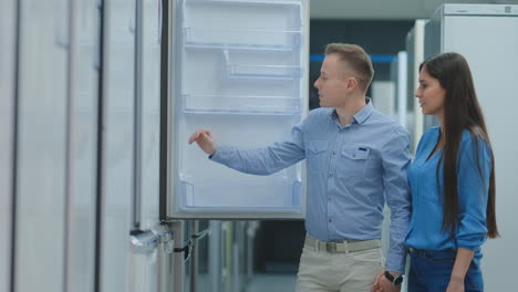 Young-couple-man-and-woman-choose-new-fridge