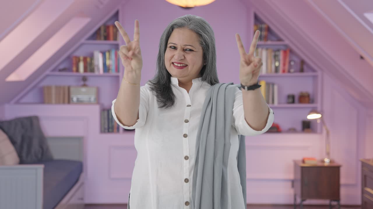 행복한 인도인 어머니는 승리의 표시를 보여줍니다.