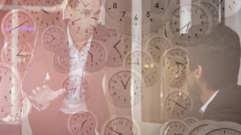 animation of moving clocks over diverse colleagues having meeting in office