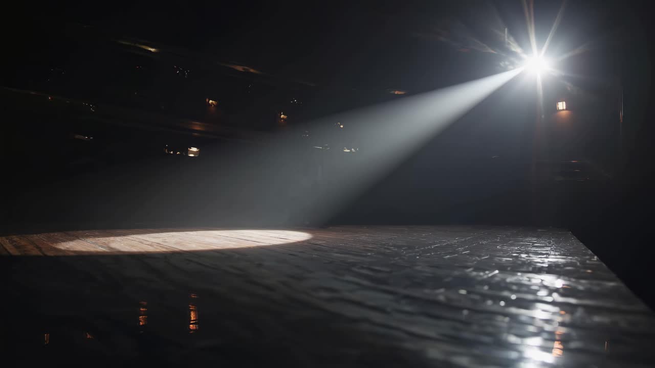 A dramatic video scene with a spotlight illuminating an empty stage