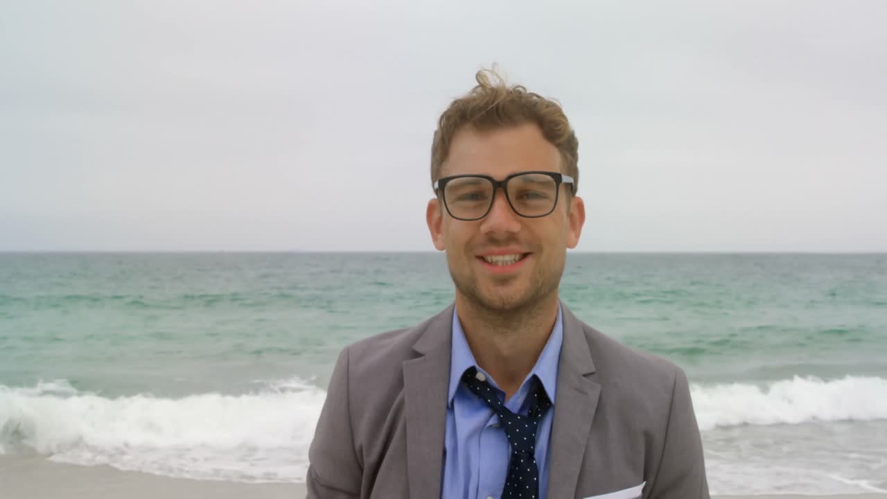 vista frontal del hombre de negocios caucásico de pie en la playa 4k