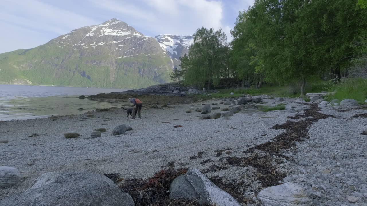 Un uomo gioca con il suo cane sulla spiaggia