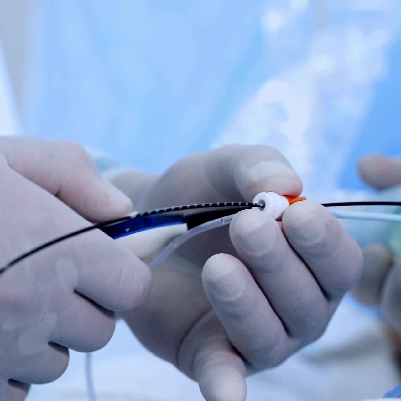 Gloved hands of surgeons holding the tools. Close up. Doctors applying the special device for vascular surgeries