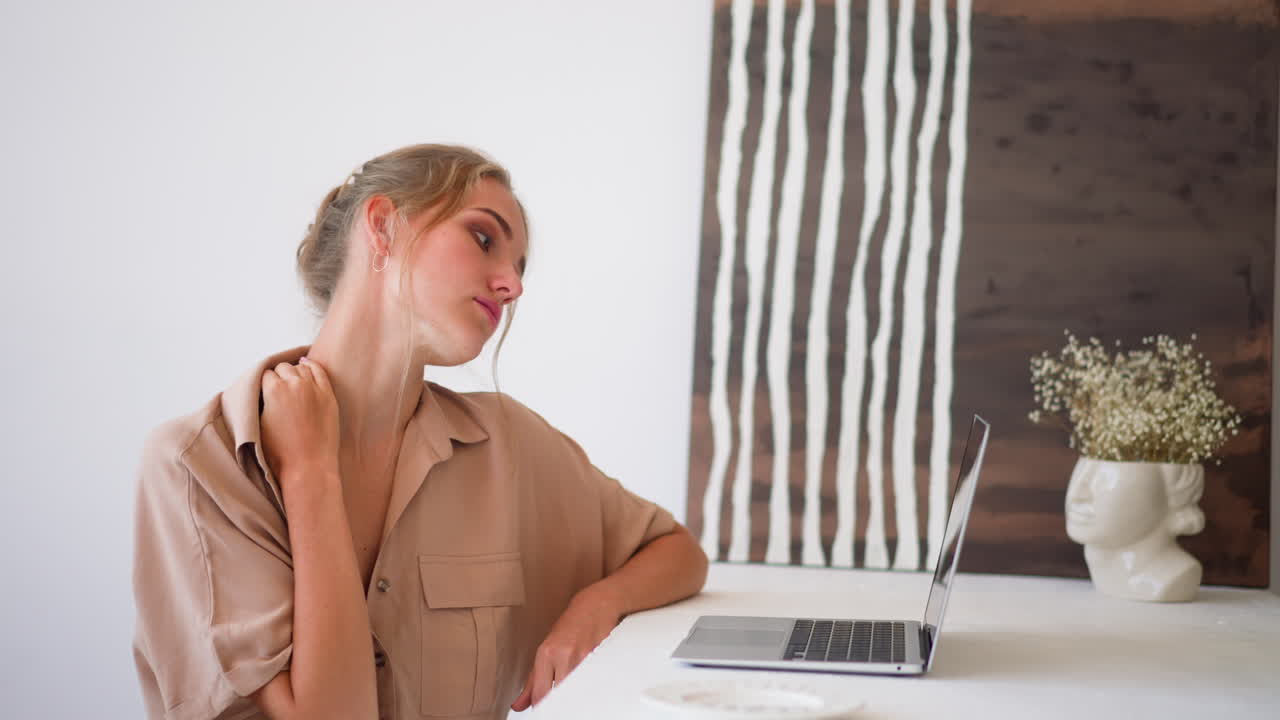 una mujer joven se siente cansada trabajando en una computadora portátil en la oficina de casa