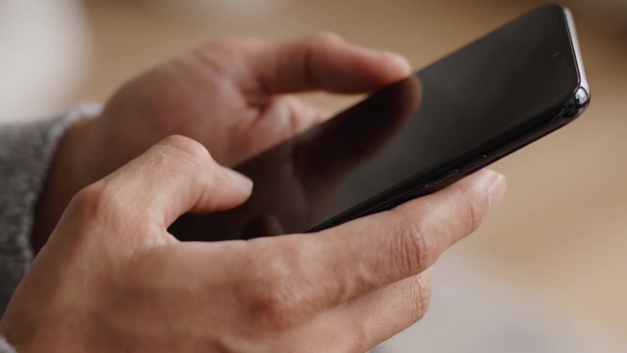Primo piano della mano di una persona che tiene uno smartphone, mostrando l'interazione con la funzionalità touchscreen e la moderna comunicazione digitale.