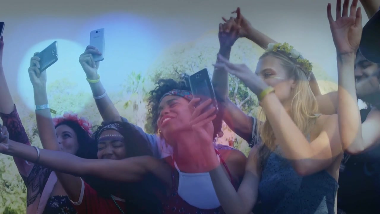 Gruppo che alza gli smartphone mentre la musica inizia, ondeggiando e filmando lo spettacolo mentre un bagliore dell'obiettivo si diffonde.
