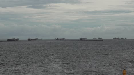 numerous cargo ships at sea on a cloudy day