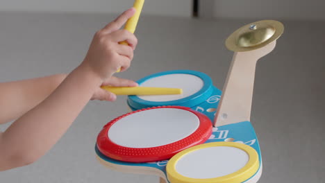 young girl playing music on toy drum set