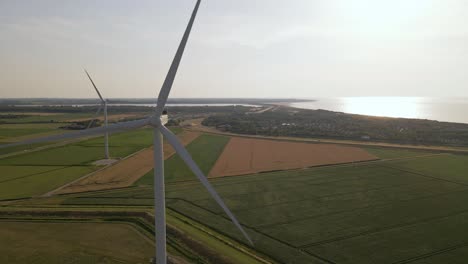 static drone footage of two rotating wind turbines near the flat coastline of south west holland, europe