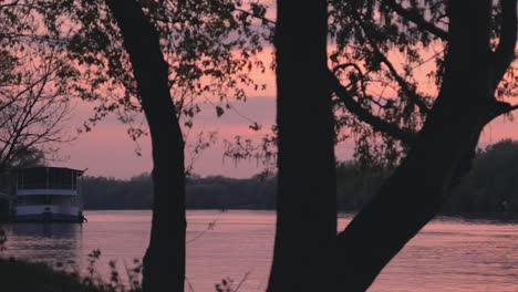 a huge white multi level river boat parking at coast of the hungarian lake tisza in the orange sunset summertime