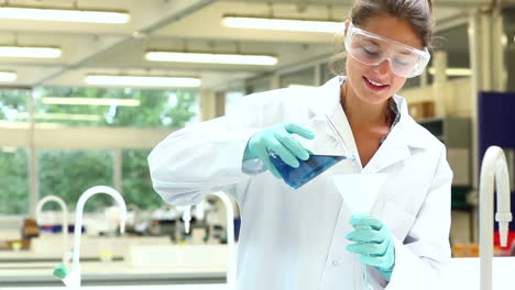 pretty science student pouring chemical through funnel