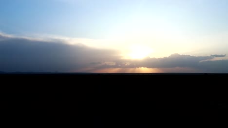 View-from-inside-a-jeep-driving-down-a-dirt-road-on-a-safari-trip,-with-a-beautiful-sunset-sky-in-the-background