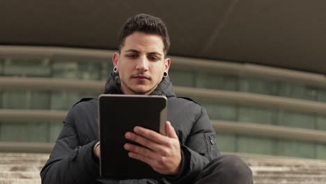 Thoughtful young man using tablet while sitting outdoor