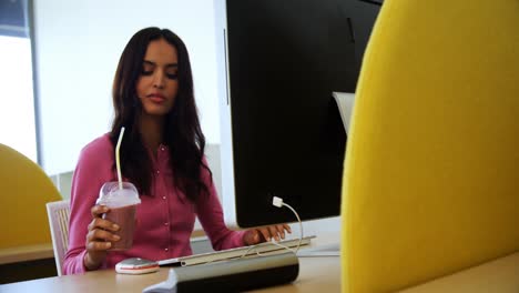 ejecutivo trabajando en una computadora personal mientras toma un batido