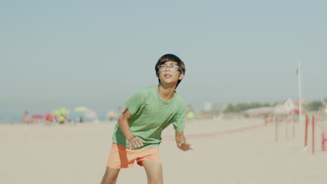 slow motion of kid kicking ball in jump and falling on sand