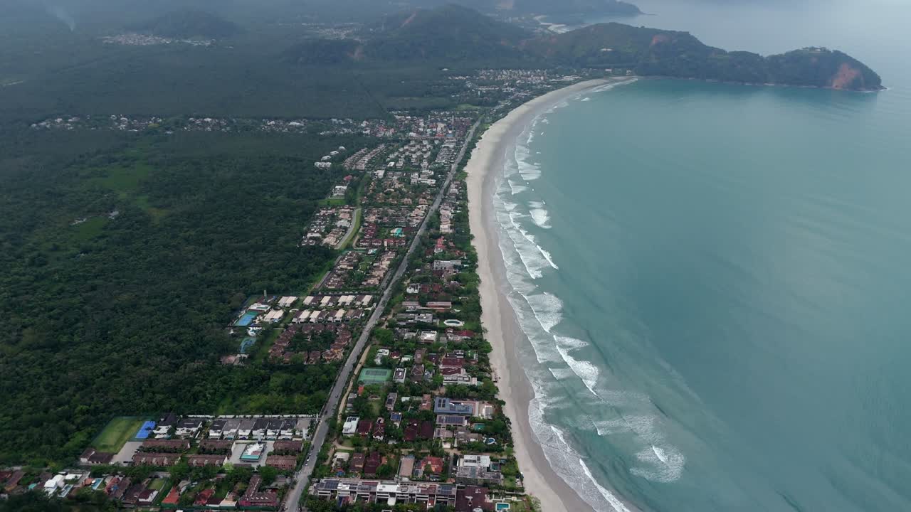Sea with waves on Sao Sebastiao beach on cloudy day, Brazil. Aerial tilt down