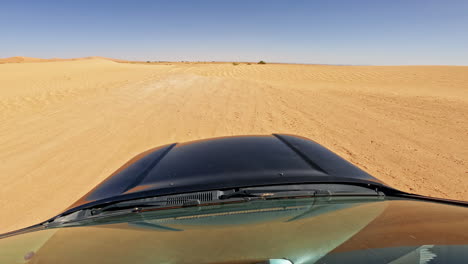 Vehículo-Todoterreno-Conduciendo-A-Través-De-Dunas-De-Arena-Del-Desierto-Bajo-Un-Cielo-Azul-Claro