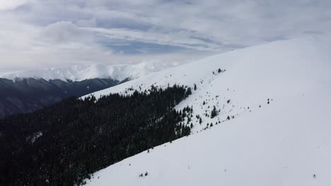 Snow-covered-Iezer-Papusa-Mountains-with-dense-forest-in-Arges,-Romania,-tranquil-nature-scene