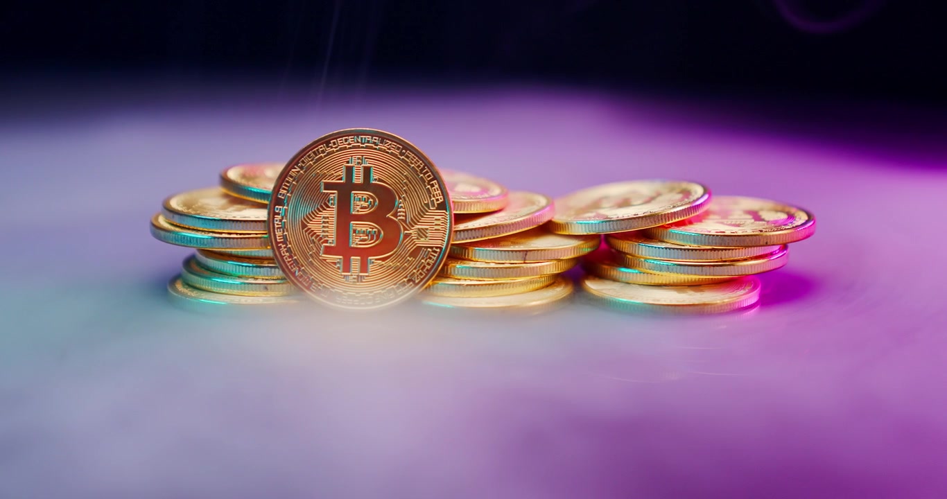 Monete di criptovaluta Bitcoin con riflessi neon colorati e fumo