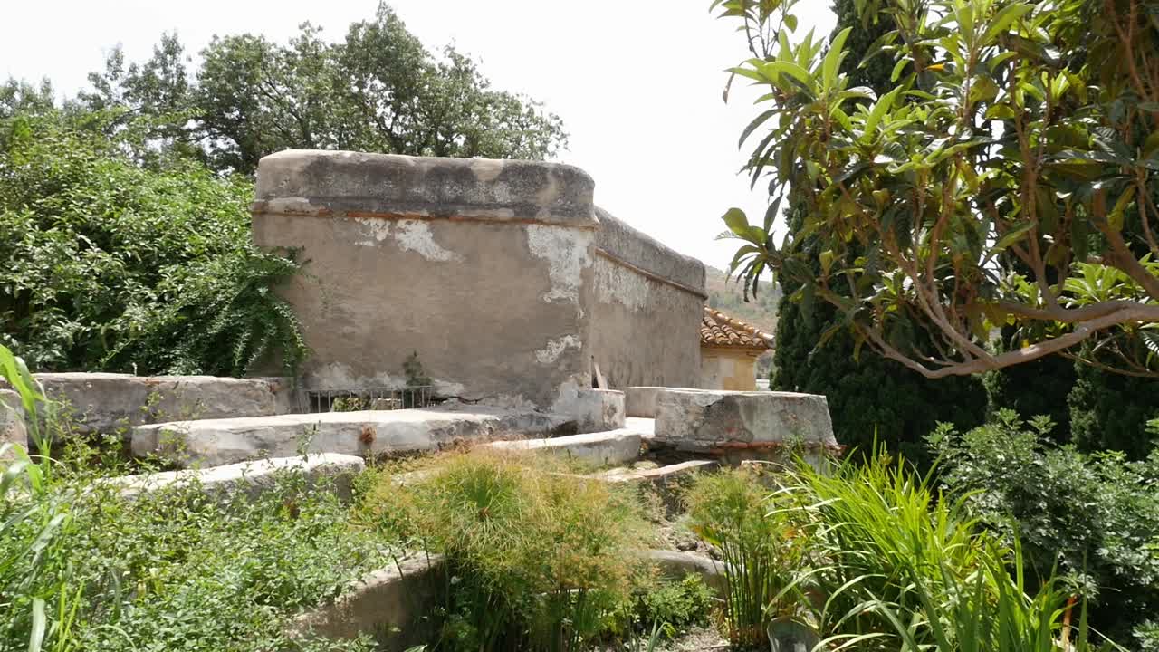 Antiche strutture in pietra e vegetazione nel Giardino Nasrid di Vélez de Benaudalla. Uno storico rifugio andaluso con architettura rustica e irrigazione tradizionale.
