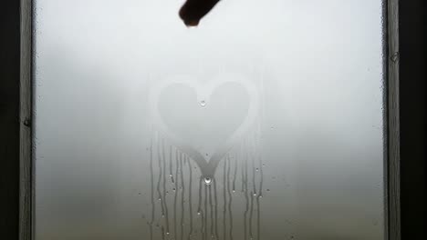 a heartfelt expression: the transformation of condensation art through a foggy window as water drops stream down the glass
