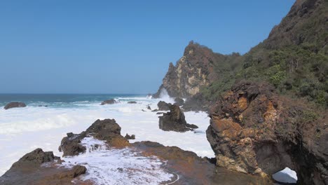 drone fly low altitude over rocky coastline with tidal waves