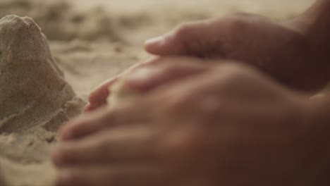 Extreme close-up shot of a girl&#039;s hand forming a sand castle on the beach - Sand Art at beach