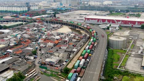 highway with semi truck jam in between factories and slums of jakarta, aerial shot