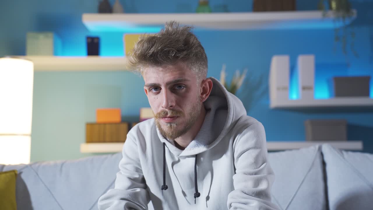 депрессивный молодой человек смотрит в камеру.