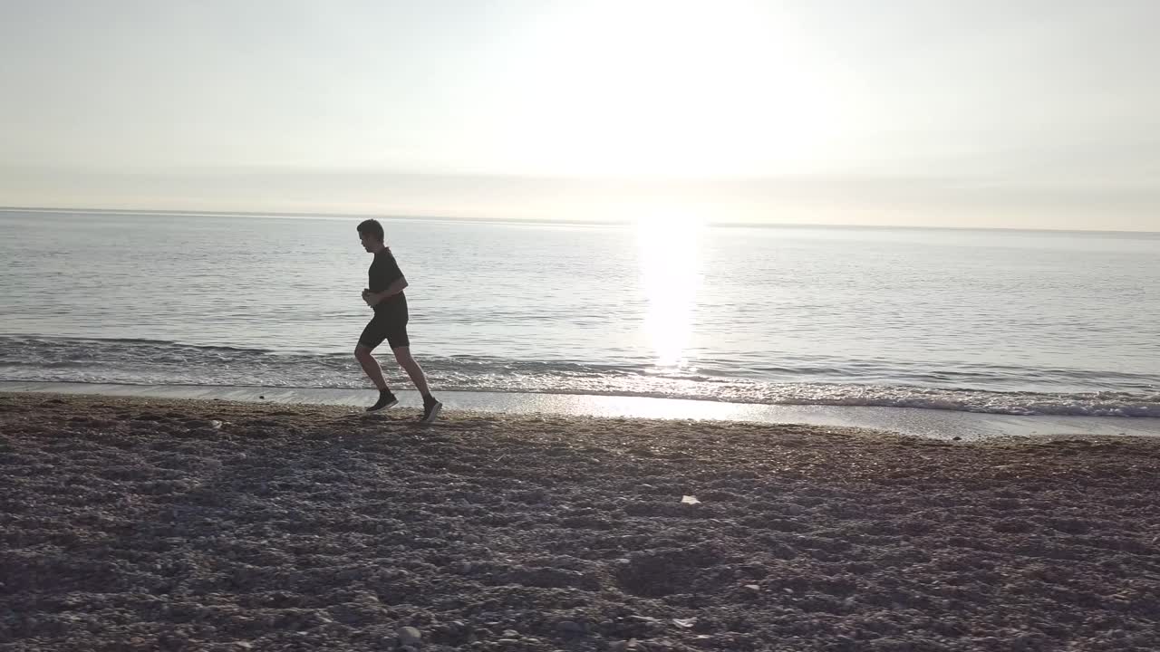 young athlete runner man with fit strong body training on beautiful Summer sunset beach sand