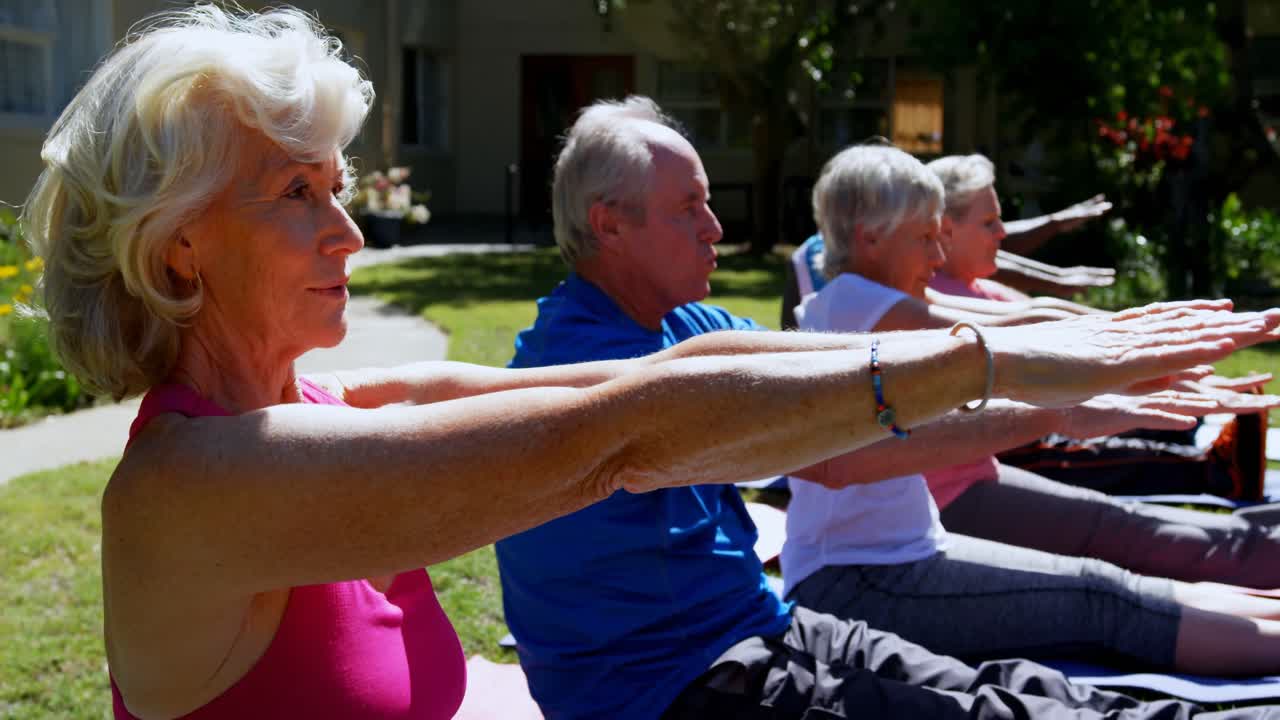 vista lateral de personas mayores activas de raza mixta realizando yoga en el jardín de un asilo de ancianos 4k