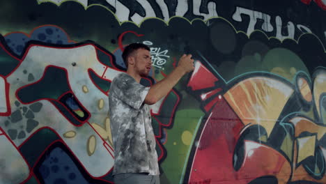 joven grabando un video en su teléfono móvil para un blog en un parque de skate con graffiti.