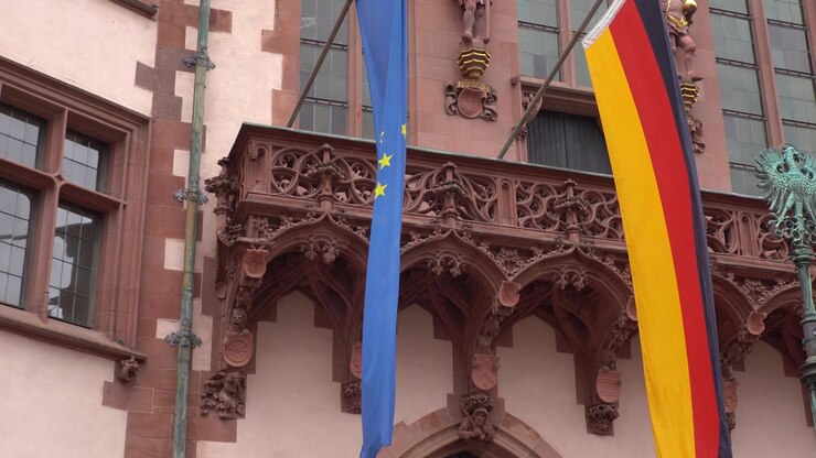 Plano detalhe das bandeiras da Alemanha e da União Europeia penduradas em um edifício histórico