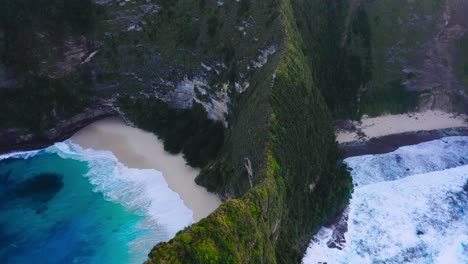 Wunderschöne-Filmische-Luftaufnahme-Von-Exotischen-Bergen,-Kristallklarem-Blauem-Wasser-Und-Wellen,-Die-Auf-Den-Strand-Von-Nusa-Penida-Kelingking-Treffen