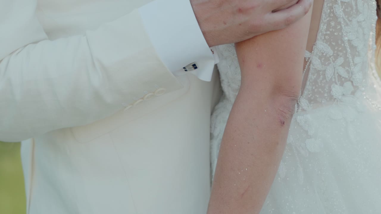 close-up of a groom's hand holding the bride’s arm, highlighting affection and the bond of marriage