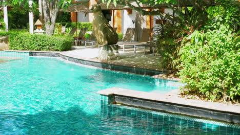 A-swimming-pool-with-turquoise-water-with-waves-under-the-morning-sun-at-a-resort-also-reveals-a-lovely-garden-with-tropical-plants