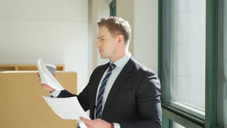 concentrated blond man in 30s reading business papers in office - dolly pull back