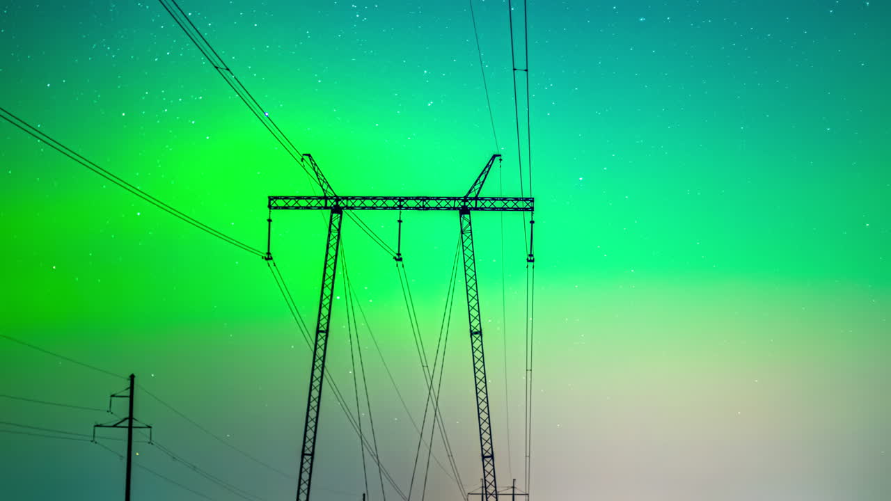 Stunning orange red blue night sky of aurora lights dancing behind electrical pylons