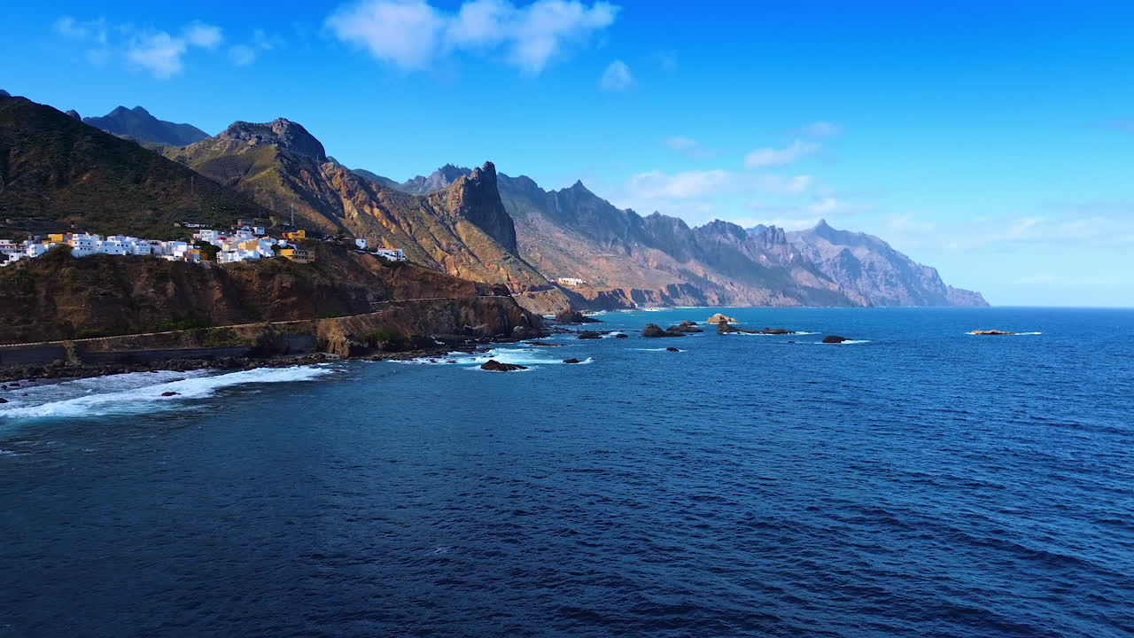 Rugged dark blue waterscape of the Atlantic Ocean at the shore of Tenerife, the Canary Islands, Spain. White villas can be seen on the rocky coast. Aerial view