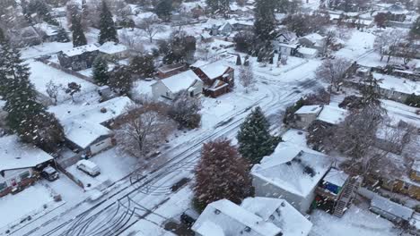 drone shot of houses covered in snow with snowflakes actively falling