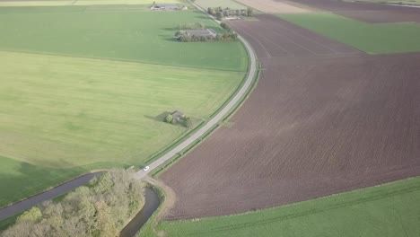 drone shot of the road surrounded by the farm fields in the netherlands