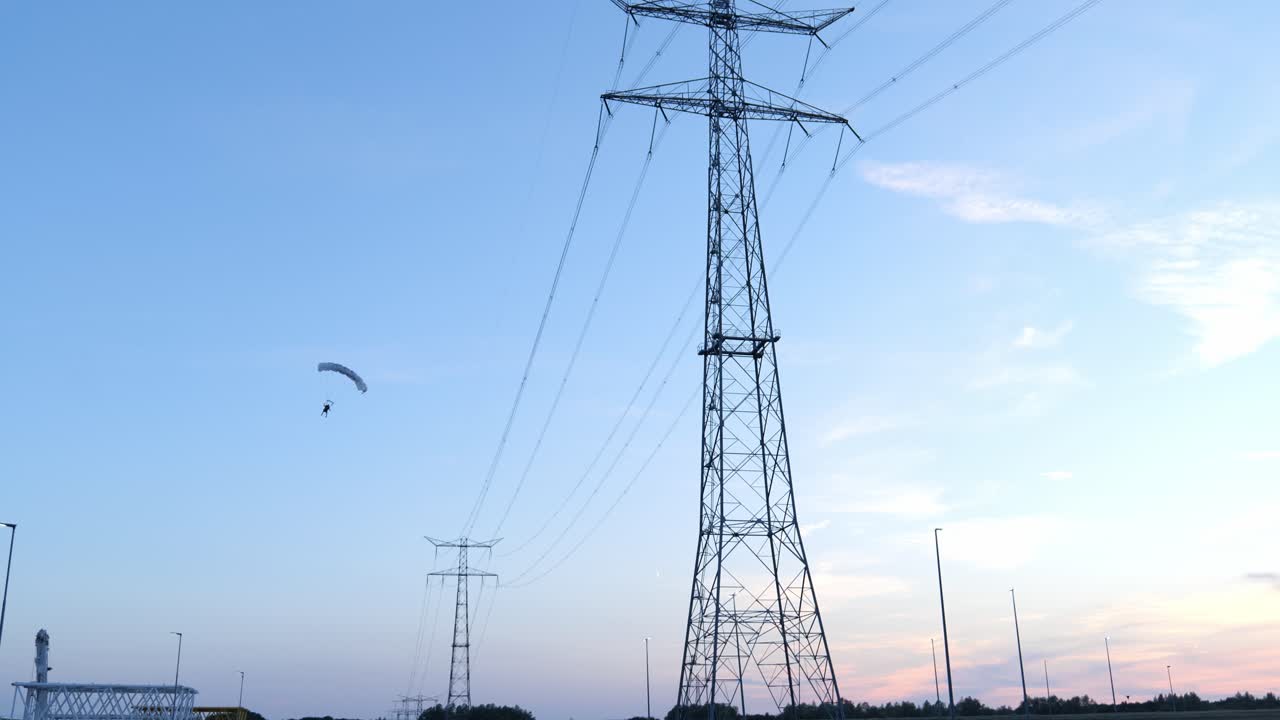 Tall power lines against a colorful sunset sky in an industrial landscape