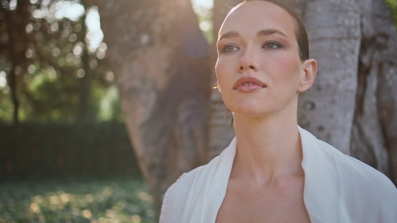 아름다운 모델이 정원을 포즈로 하고 자연의 아름다움을 근접적으로 바라보고 있습니다. 나무 에 있는 여성